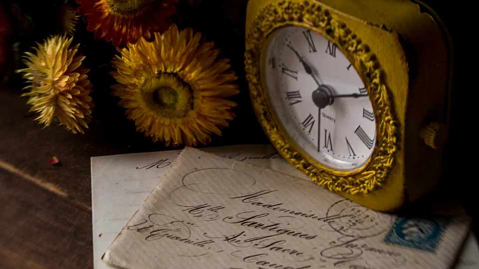 Relógio antigo sobre cartas e flores secas