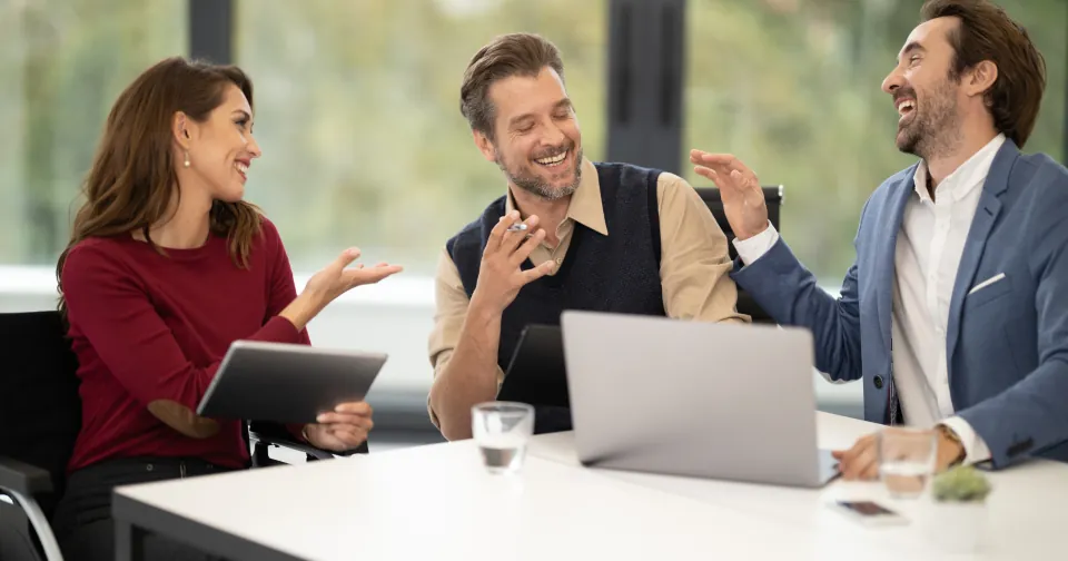 Três pessoas sorrindo numa reunião de negócios