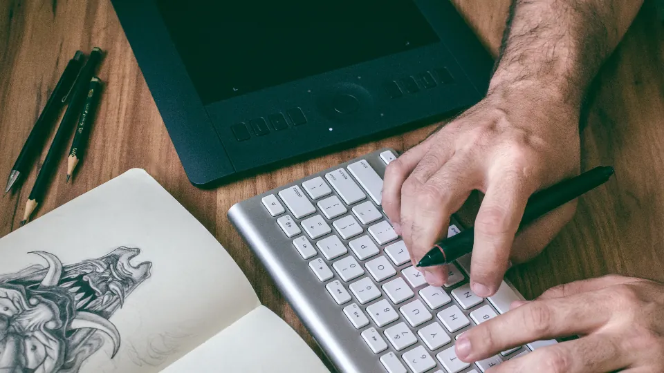 Designer desenhando um logotipo à mão, ao lado do teclado