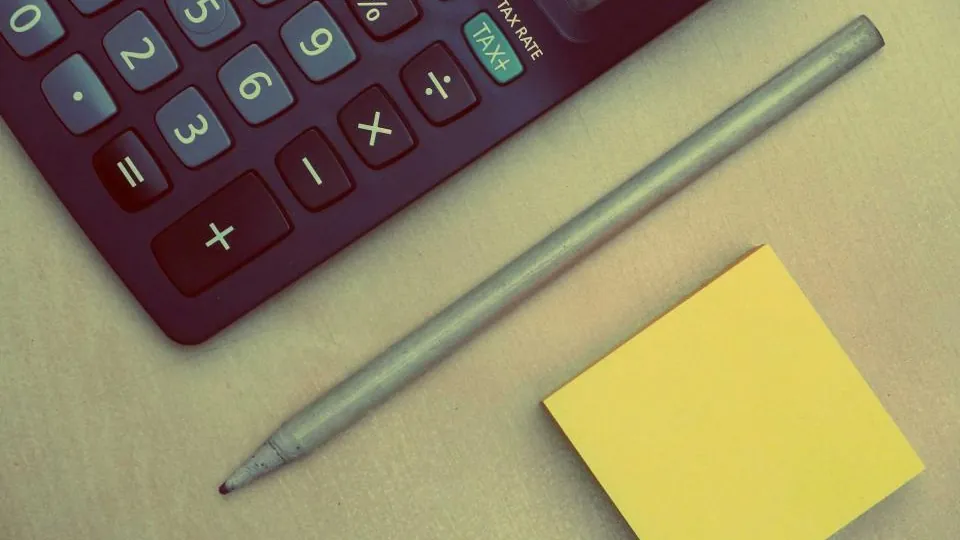 Calculadora, lápis e bloco de notas sobre a mesa