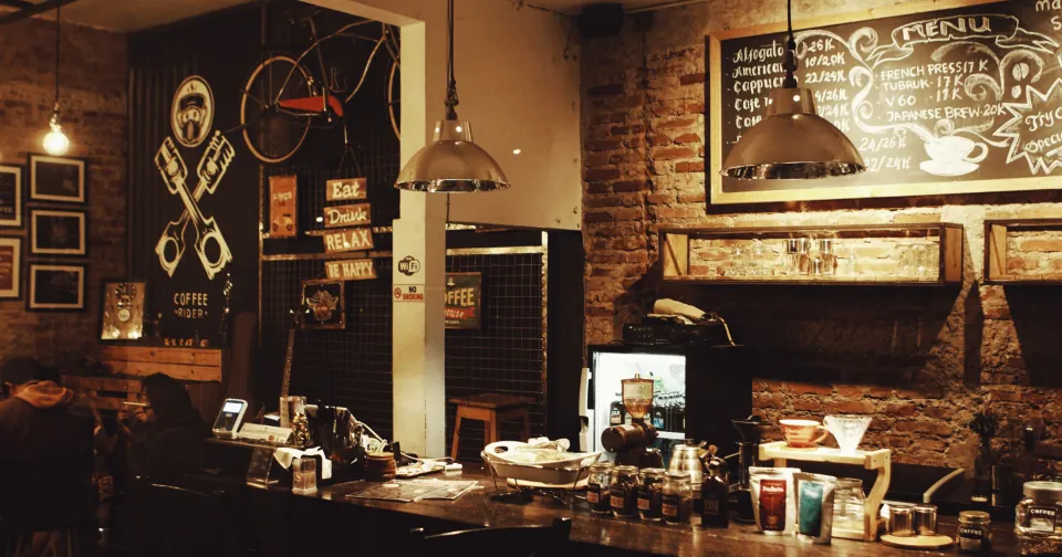 Interior de uma pequena cafeteria com balcão e quadro-negro