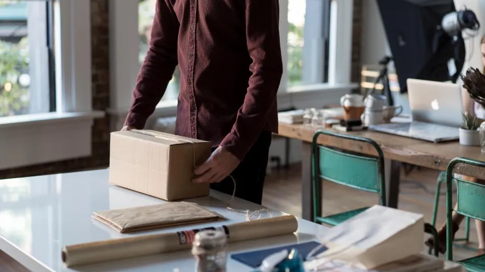 Empreendedor embalando um pedido na mesa de trabalho